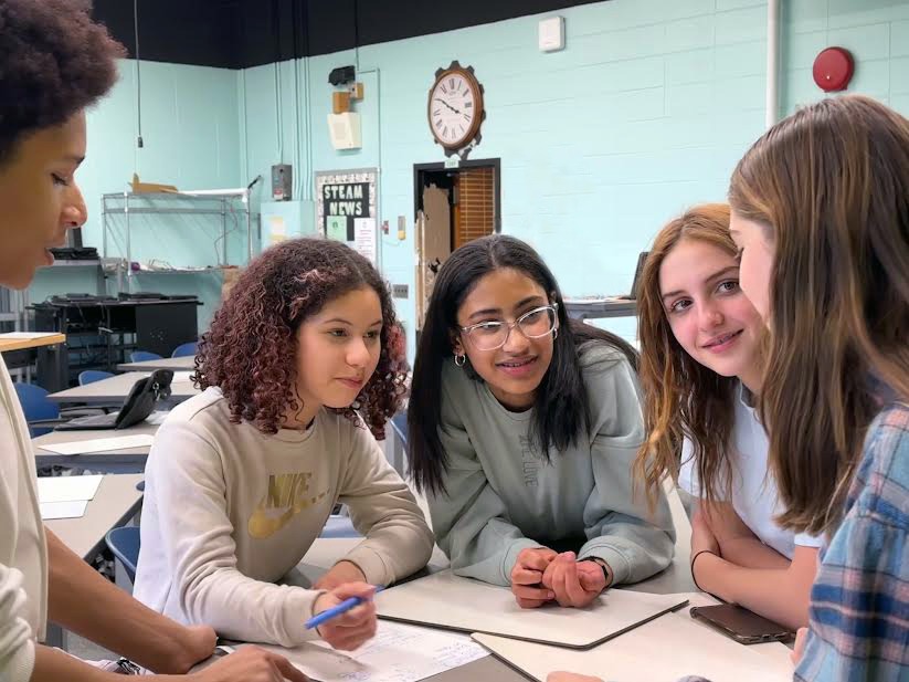 Young people collaborating around a table in a classroom